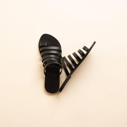 Harmonia womens leather flats in black against a beige background. They are flat sandals luxury brand.