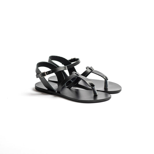 Pair of black designer flat sandals on a white background. They are flat sandals one strap.