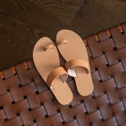 Pair of beige sandals women's on a woven brown mat