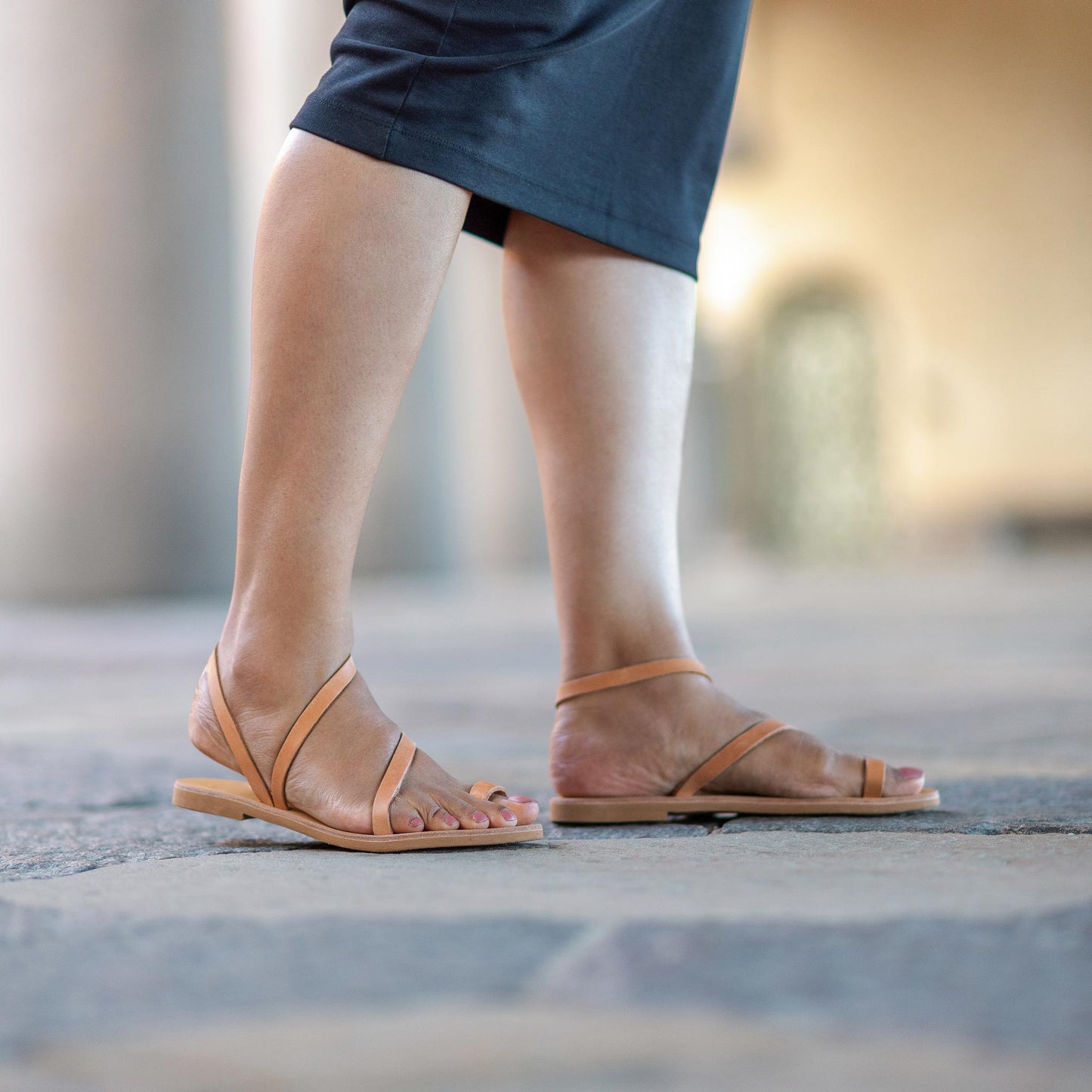 Woman wearing tan flats sandals on a blurred background