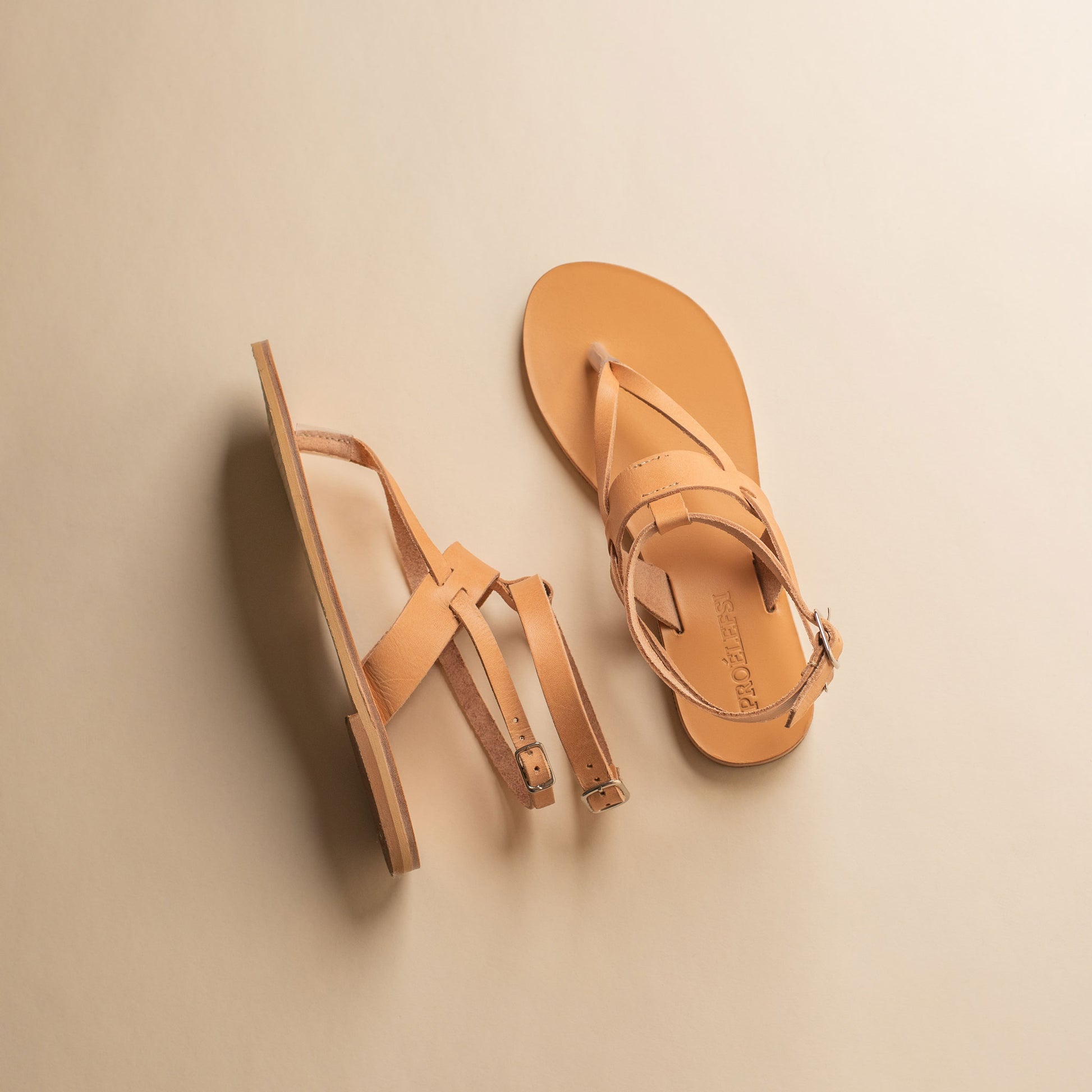 Pair of tan double strap sandals on a beige background