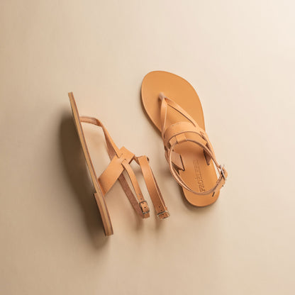 Pair of tan double strap sandals on a beige background