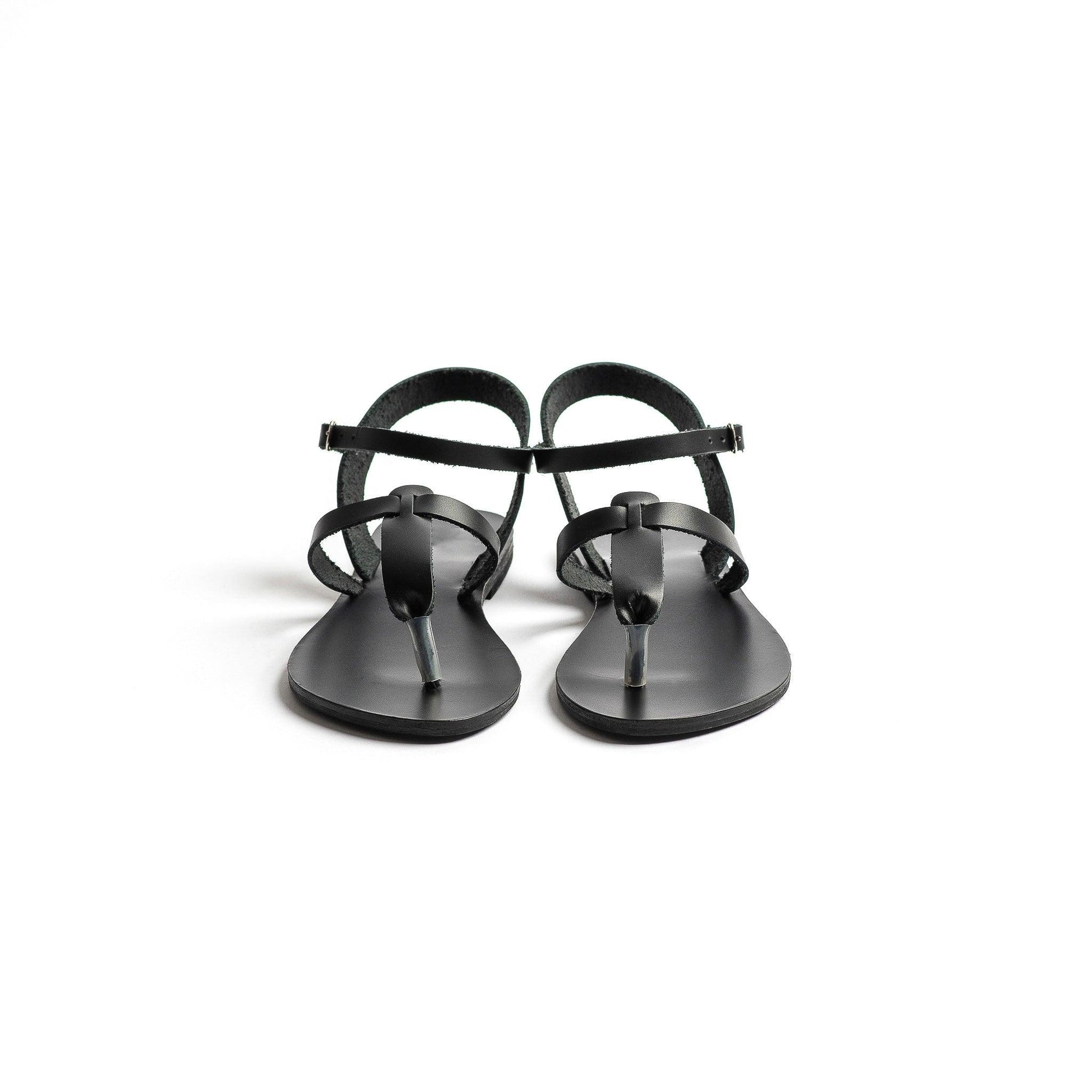 Pair of black flat sandals ankle strap on a white background-front view